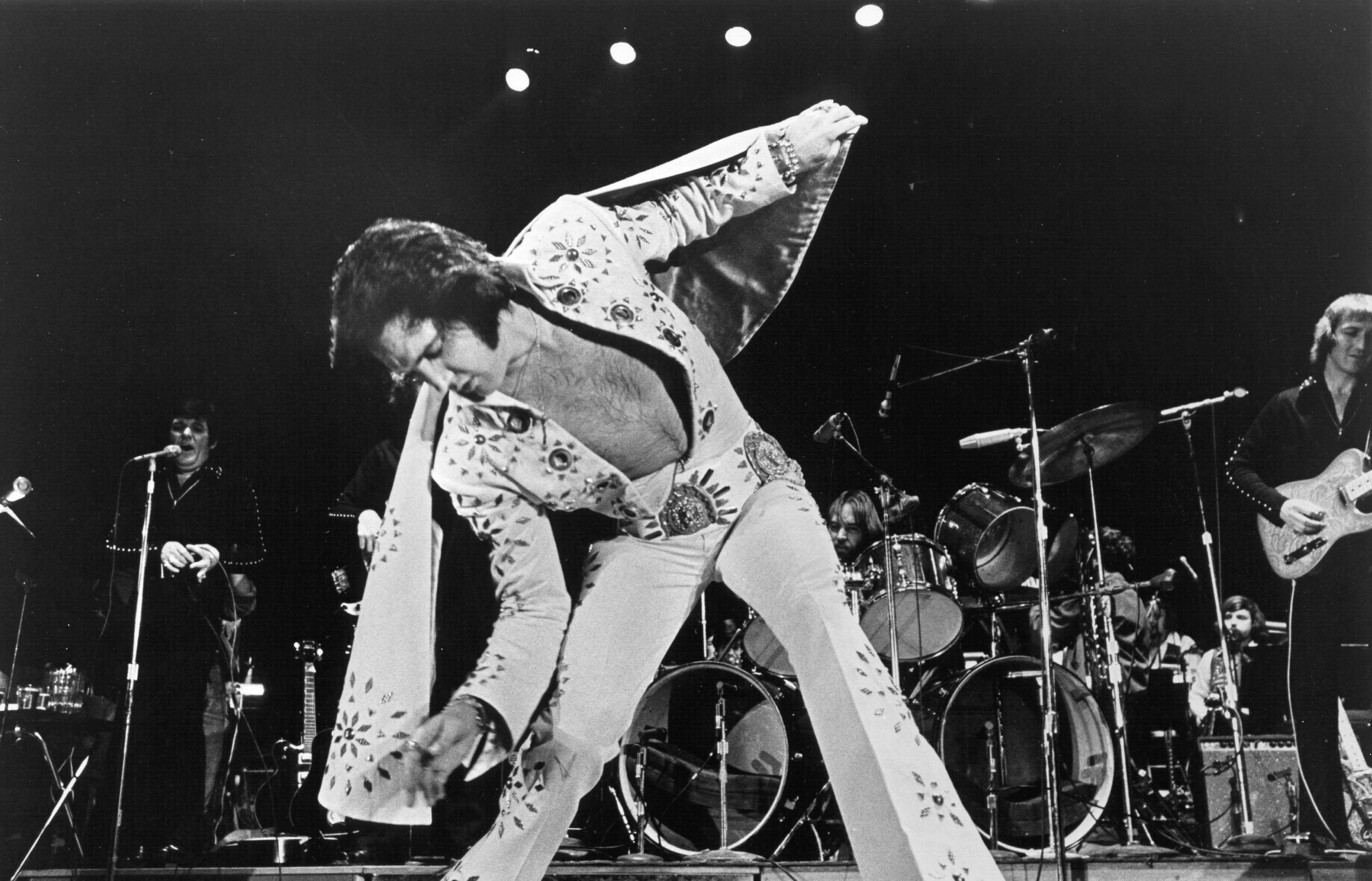 Elvis Presley sfoggia la sua iconica tuta di strass mentre si esibisce.
