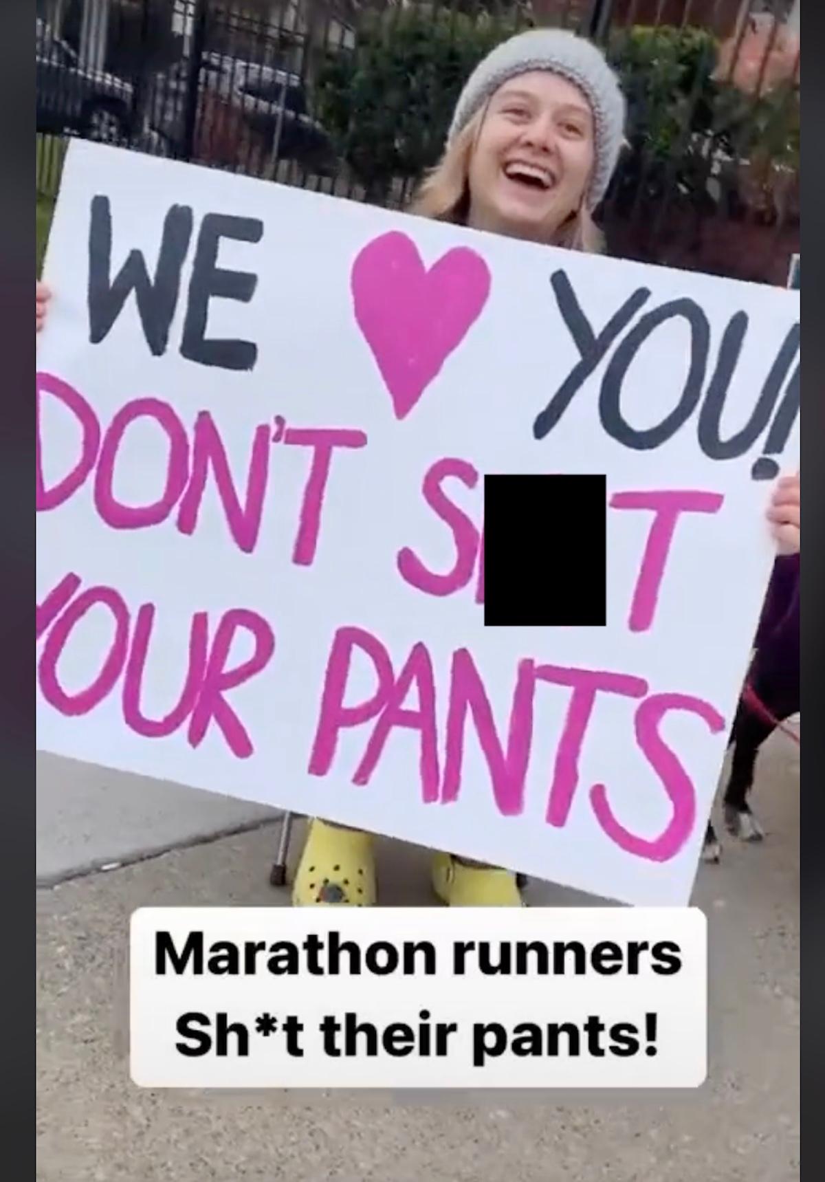 uma mulher segurando uma placa que diz "Nós amamos você, não cague nas calças."