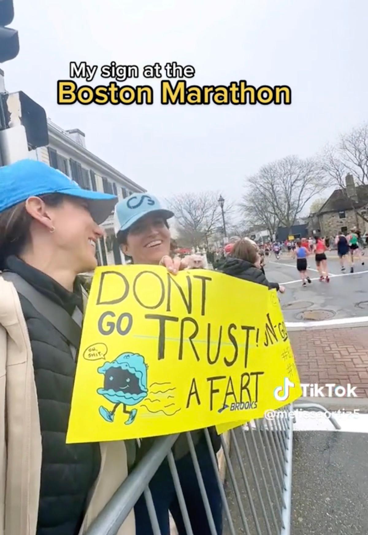举着牌子的女人说 "不要相信一个屁" 在马拉松比赛中