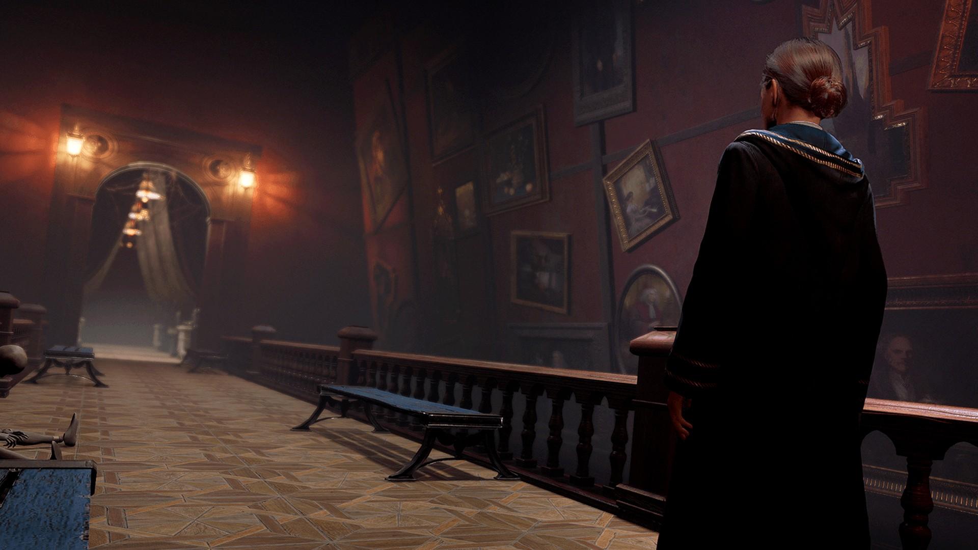 En heks, der stirrer ned ad en lang snoet gang med malerier i 'Hogwarts Legacy'.