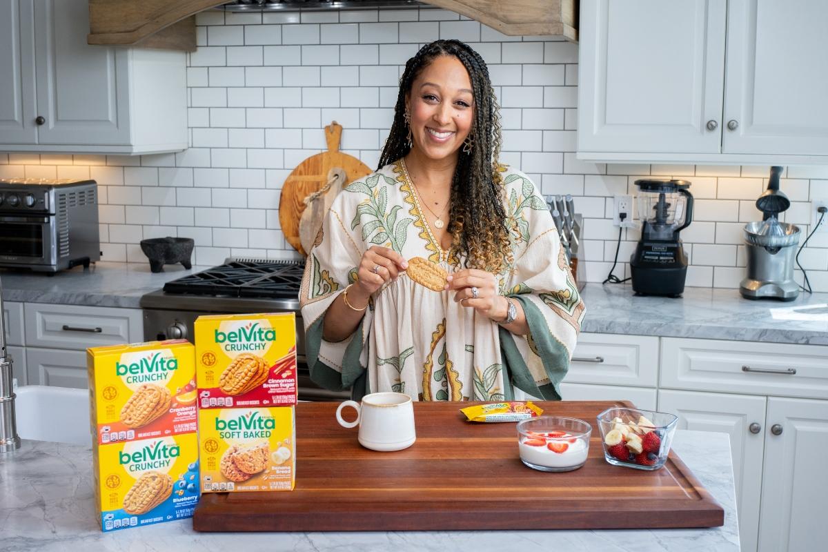 Tamera Mowry-Housley pose avec des biscuits pour le petit-déjeuner belVita dans une cuisine.