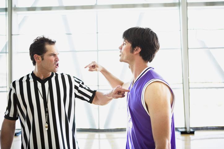 Ein Basketballspieler und ein Schiedsrichter werden in einem Streit auf dem Spielfeld gesehen.