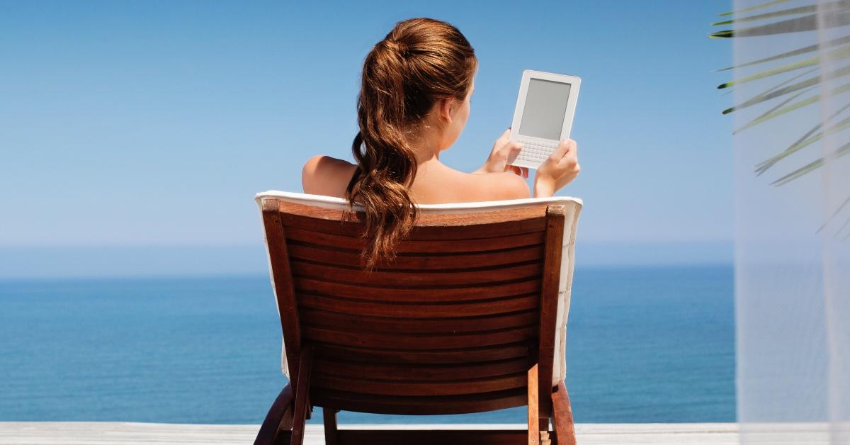 휴가에 e-reader를 사용하여 읽는 여자. 