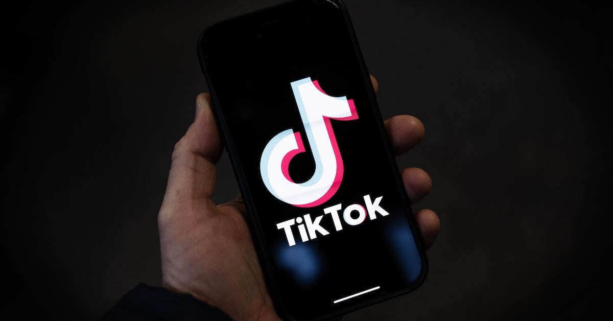 En person som håller en smartphone med TikToks logotyp visas