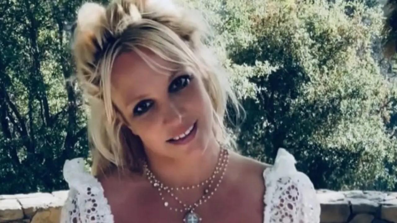 Britney Spears smiler udenfor i en blondeskjorte