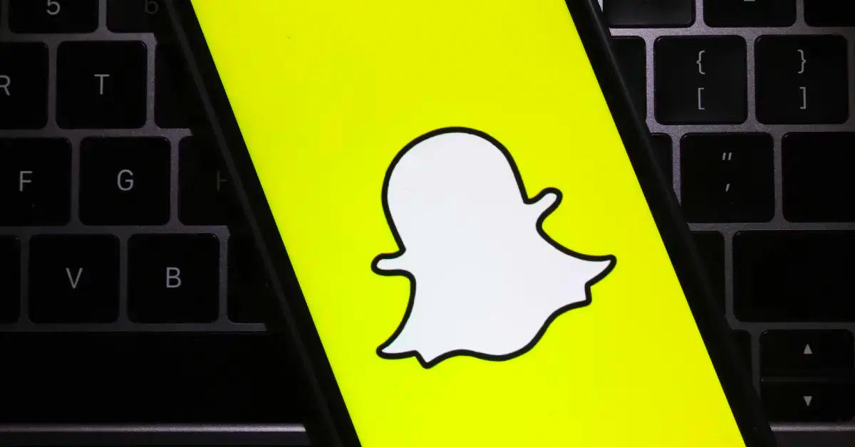 Et Snapchat-logo, der fylder hele skærmen på en telefon med et tastatur i baggrunden. 