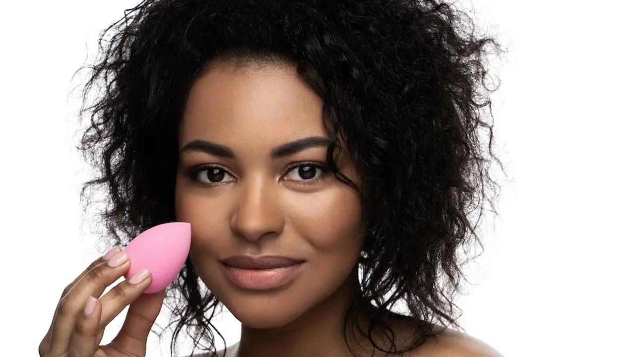 Uma mulher segurando uma esponja de maquiagem