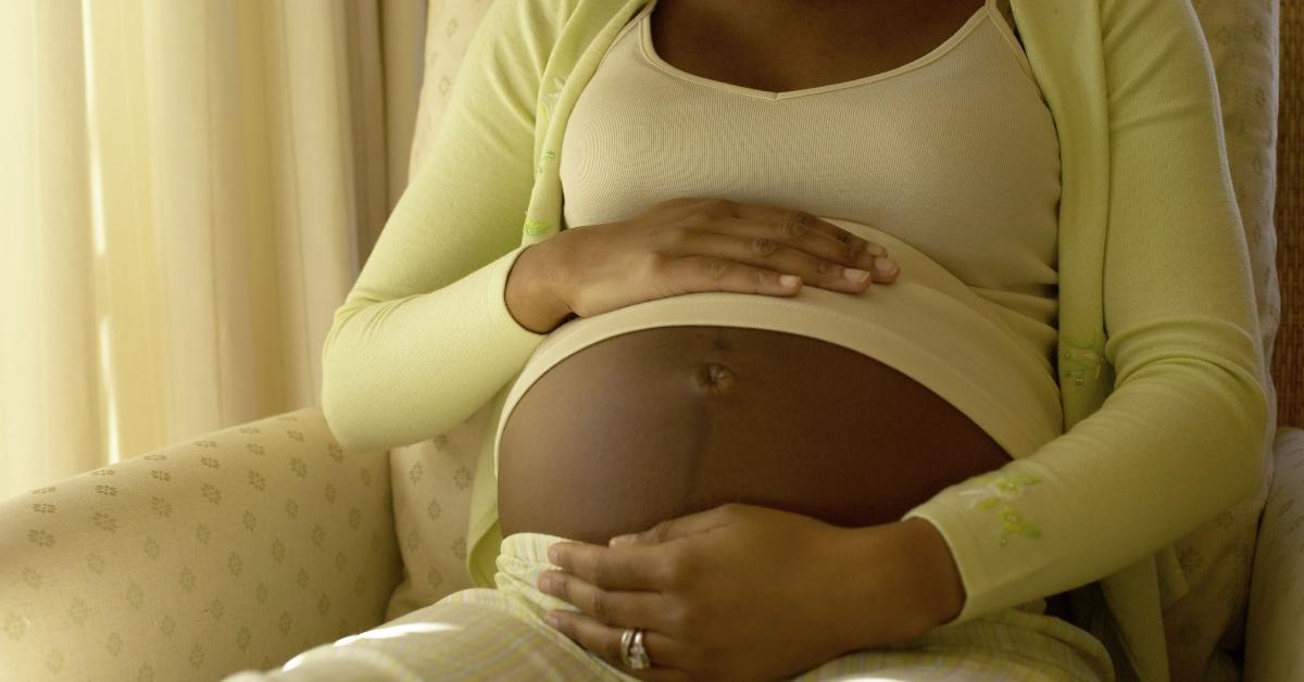 Mulher negra embalando a barriga do bebê