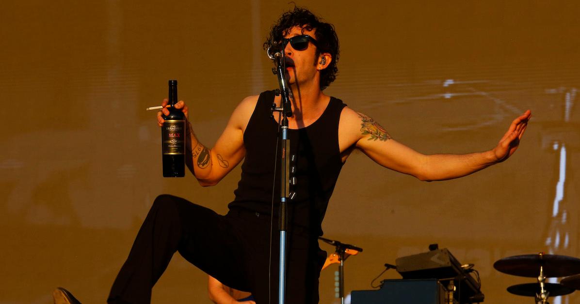 Matty Healy se apresentando no palco segurando uma garrafa de álcool