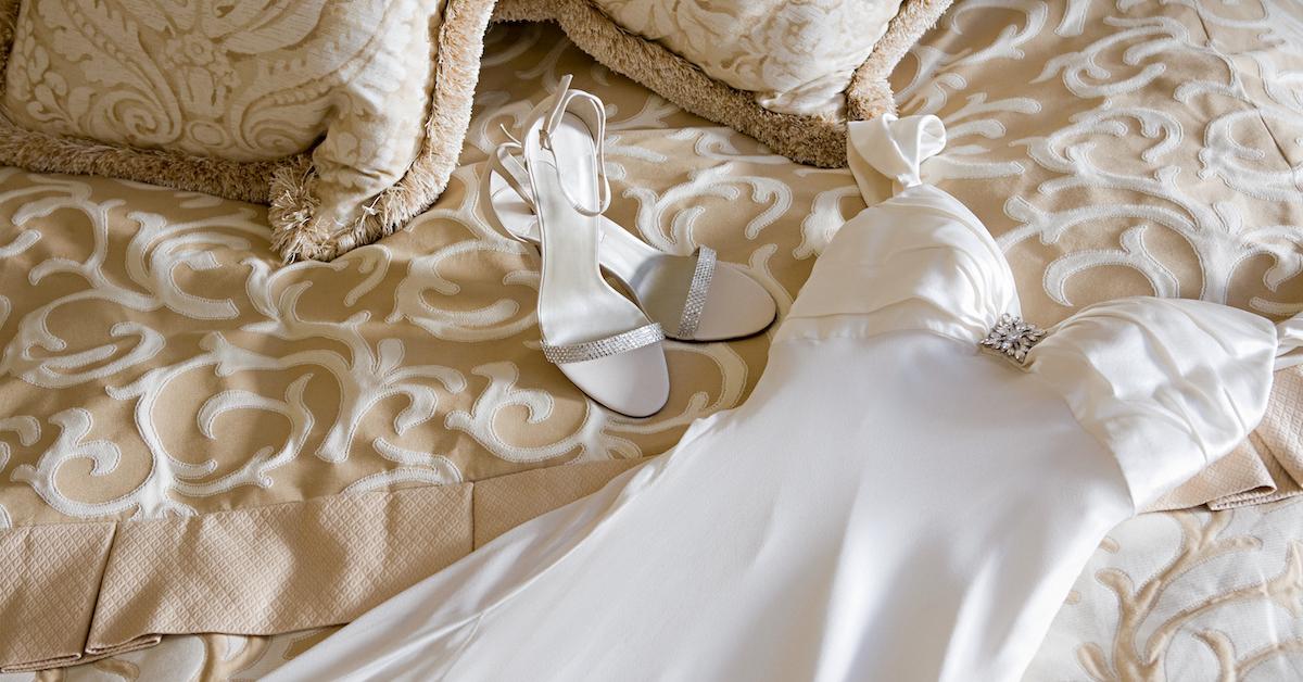 Un abito da sposa sdraiato sul letto con le scarpe