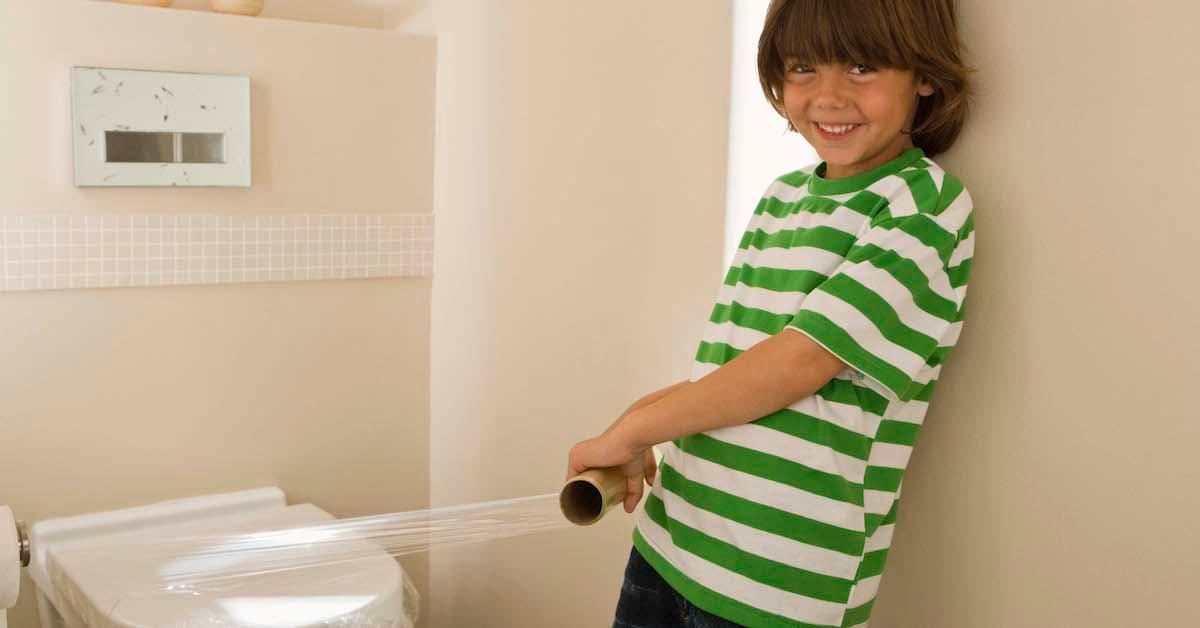Un bambino che mette la pellicola trasparente su una toilette