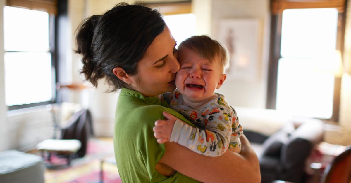 Una madre che tiene in braccio il figlio che piange.