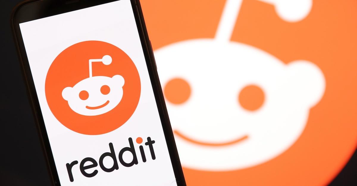 携帯電話と背景にある Reddit のロゴ