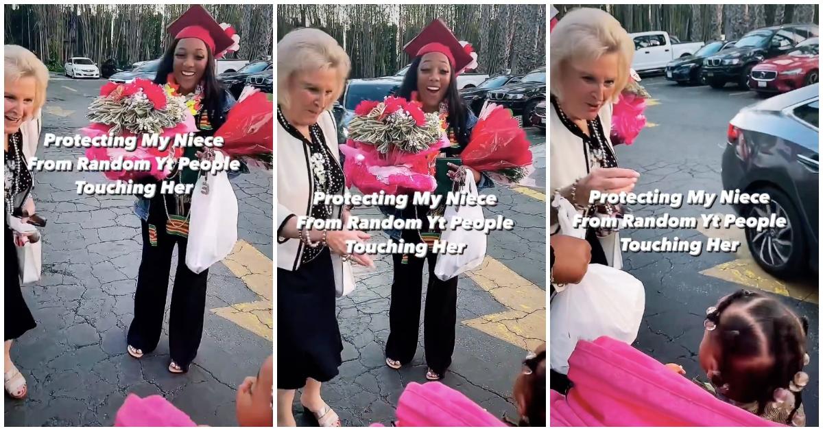 Weiße Frau versucht, schwarzes Kleinkind im Kinderwagen zu berühren, die Mutter des Kleinkindes hält Abschlussgeschenke in der Hand.