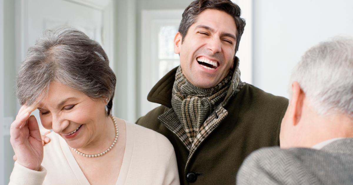 Ein Mann lacht mit seinen älteren Eltern.