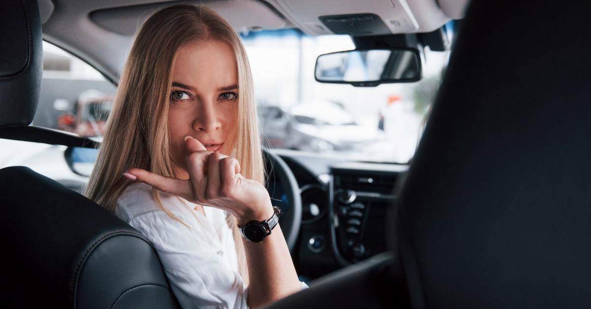 Eine Frau zeigt mit dem Finger und dreht sich zum Rücksitz ihres Autos.