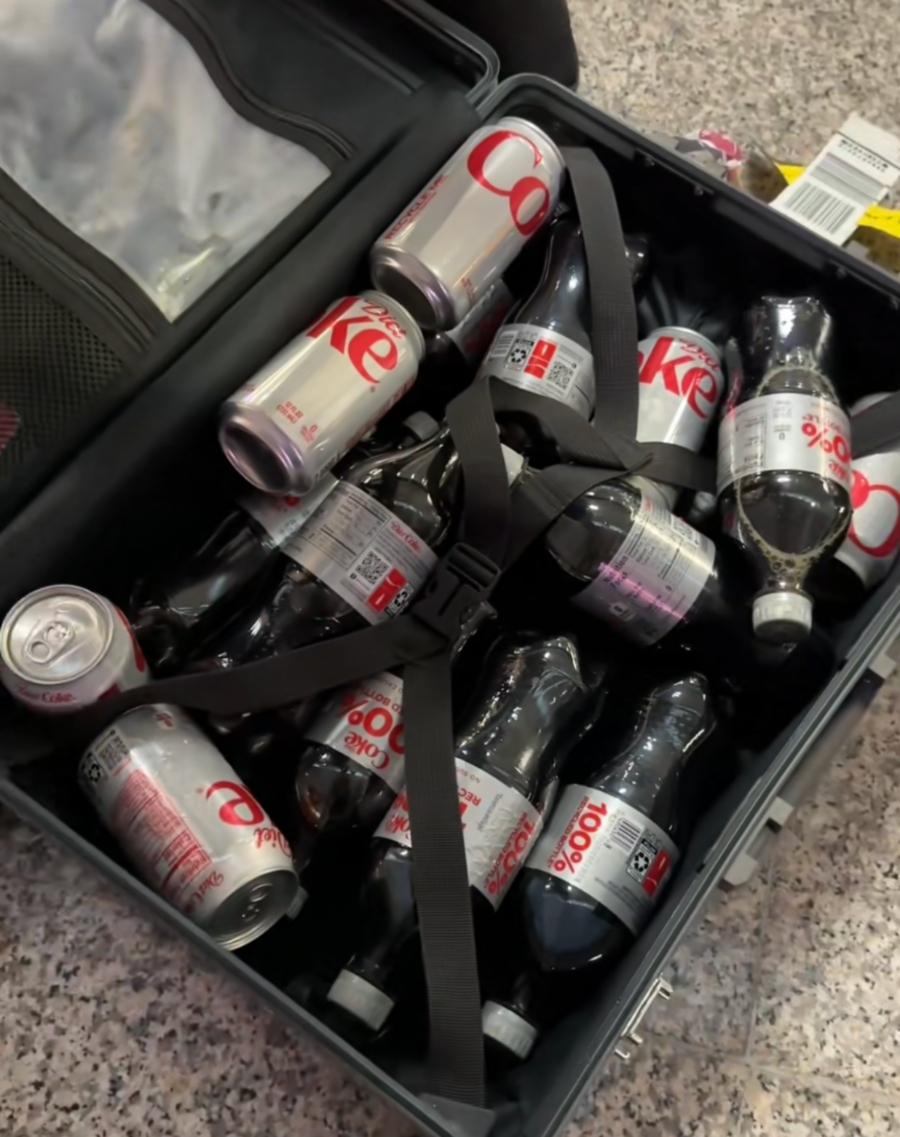 En kvinnas resväska fullpackad med Diet Coke burkar och flaskor