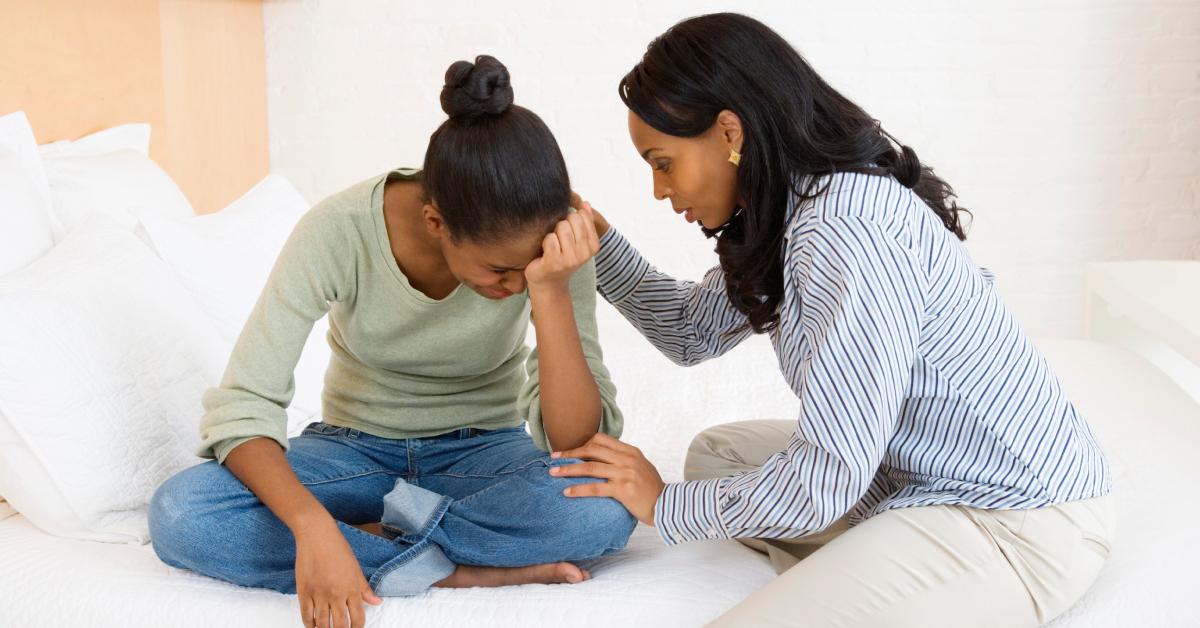 Uma mãe consola sua filha adolescente que chora.