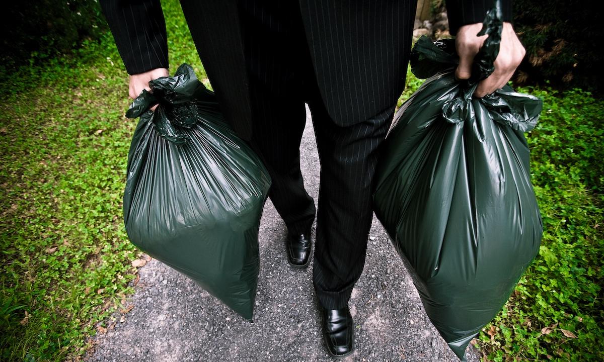 Una persona con in mano due sacchi della spazzatura