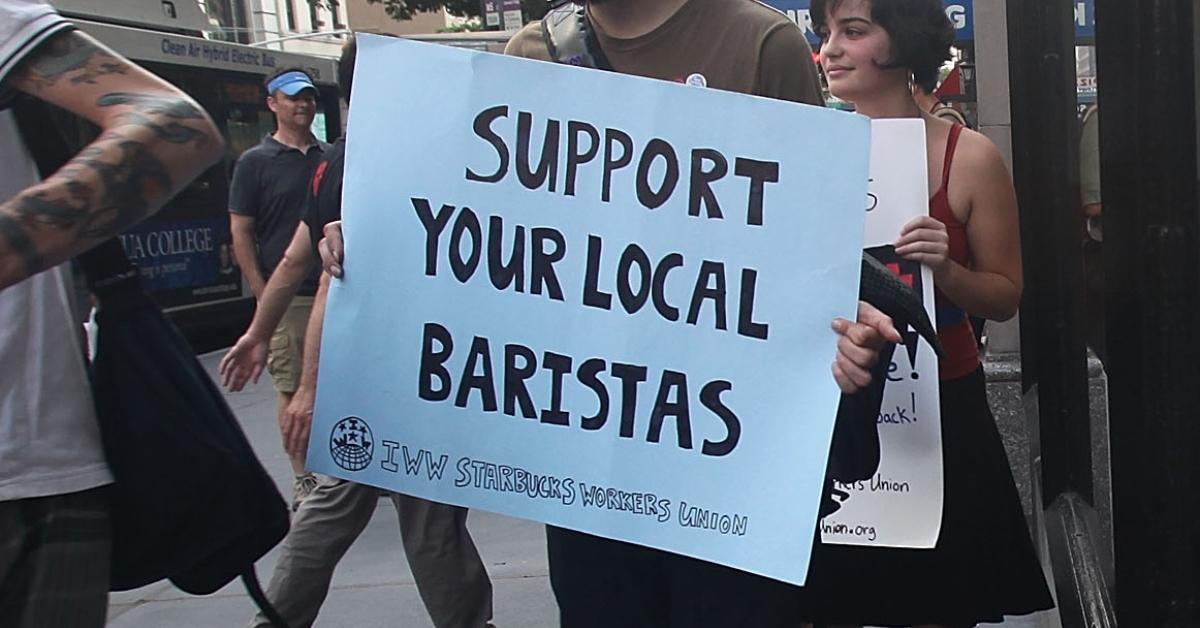 Une personne tenant une pancarte pour soutenir les baristas lors d'une manifestation devant un Starbucks