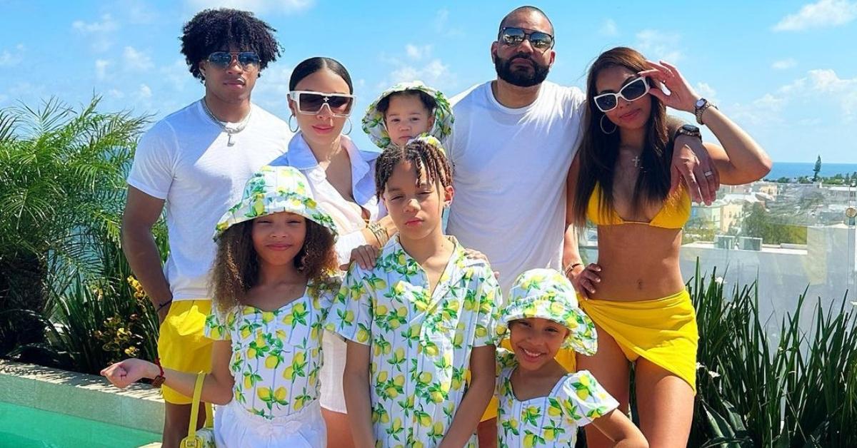 DJ Envy 和 Gia Casey 与他们的六个孩子在泳池边合影，他们穿着相配的柠檬印花服装和泳衣。