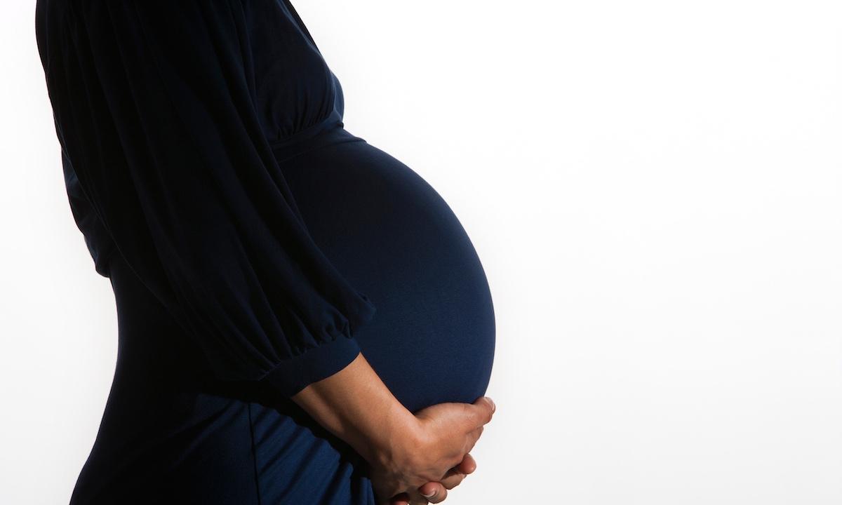 Une femme enceinte berçant son ventre.