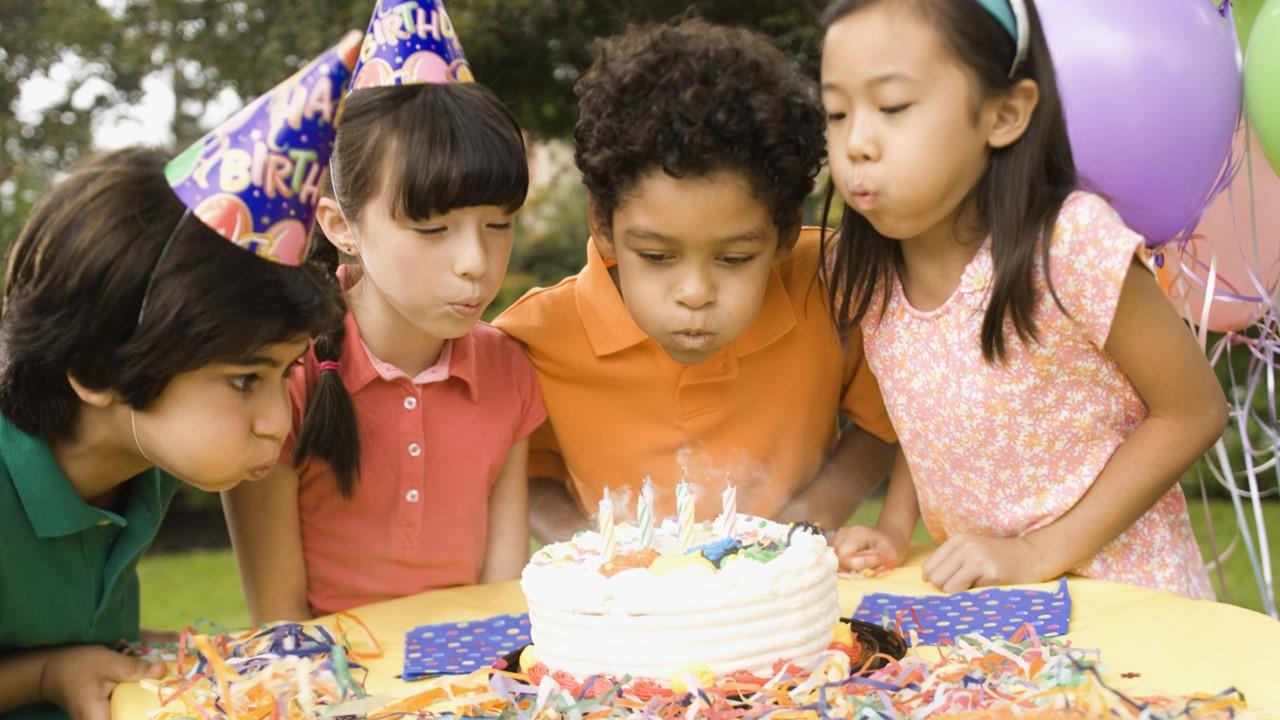 Bambini che spengono le candeline su una torta di compleanno