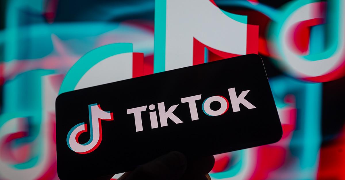 Et TikTok-logo på en skærm med et logo bagved. 