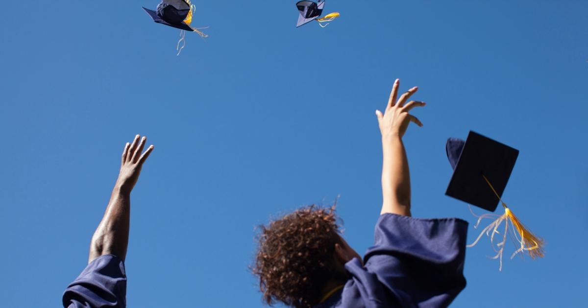 卒業を祝って帽子を空中に投げ上げる大学卒業生