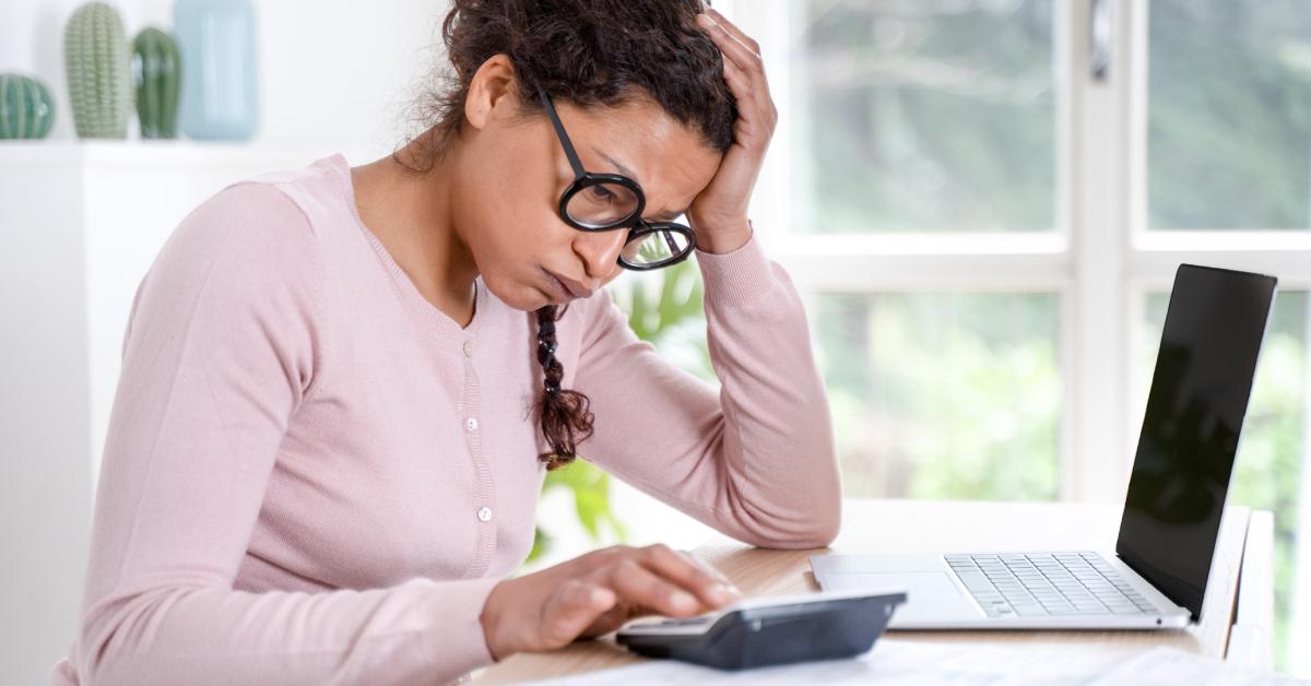 Eine Frau ist gestresst, während sie auf ihre Rechnungen schaut.