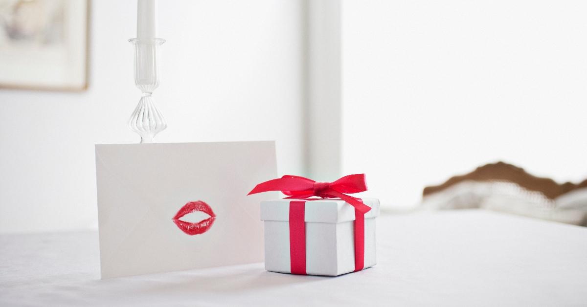 Confezione regalo con nastro e biglietto con bacio di rossetto sulla scrivania - foto d'archivio