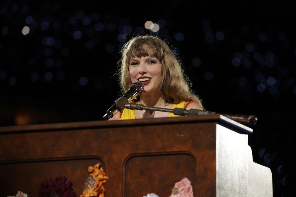Taylor Swift usando o vestido amarelo enquanto canta músicas surpresa