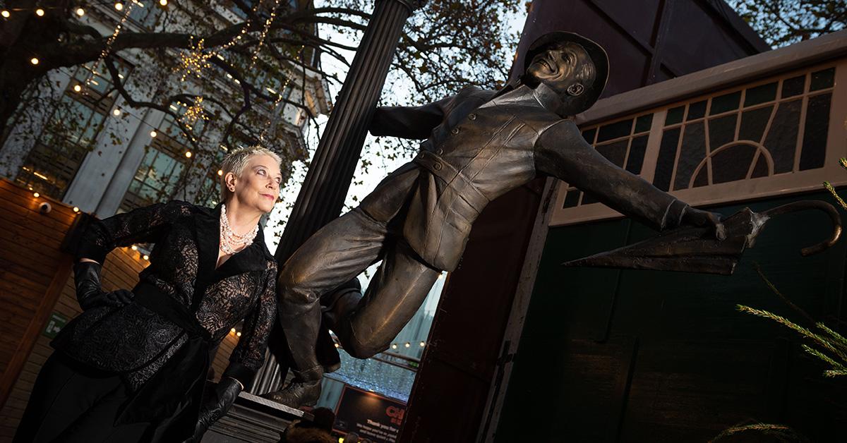 Patricia Ward olhando para uma estátua de Gene Kelly. 