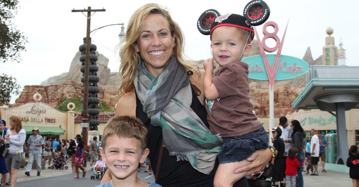 셰릴 크로우(Sheryl Crow)와 그녀의 아들들이 디즈니 캘리포니아 어드벤처 파크의 Cars Land에서 포즈를 취하고 있습니다.