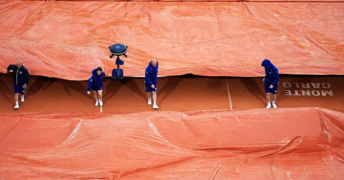 Les travailleurs du tournoi couvrent un terrain en raison de la pluie en 2024